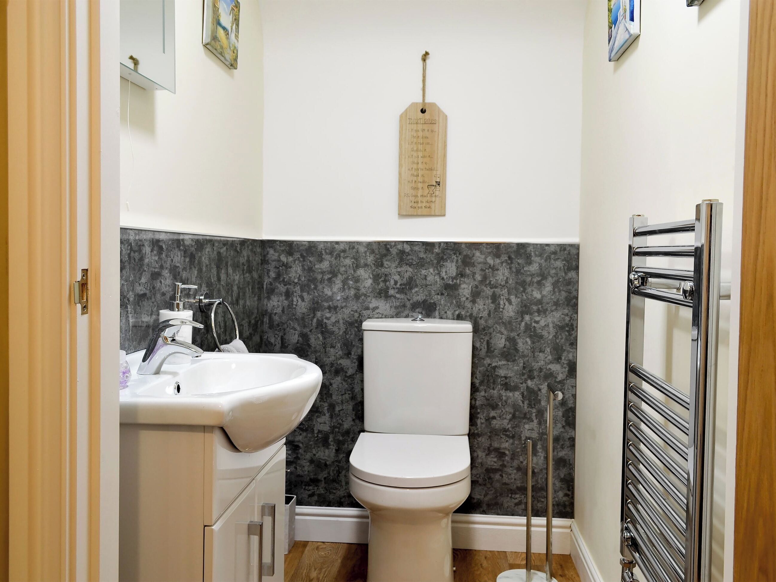 Een moderne badkamer met een wit wastafel, een chromen kraan en een toilet tegen een gestructureerde grijze muur.