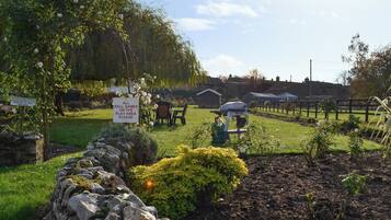 A garden with a stone wall, a grill, and a sign prohibiting dogs.