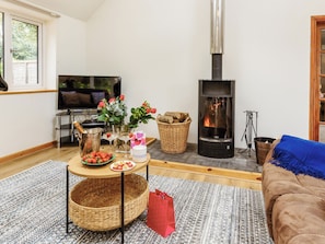 A living room with a fireplace, a television, a sofa, and a table with various items.