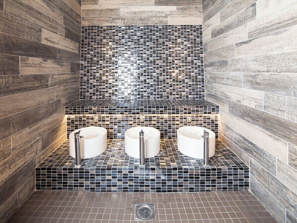 A bathroom with three sinks, a tiled backsplash, and wooden walls.