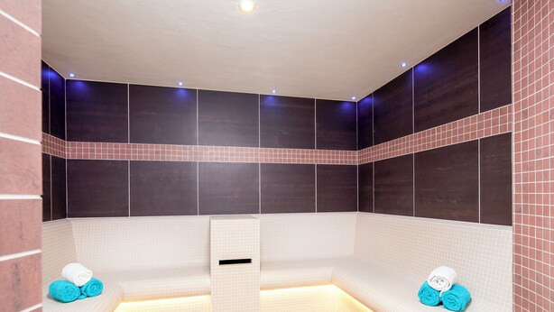 Un spa moderno con suelo calefaccionado, un banco y toallas.