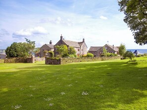 A stone building with a grassy lawn and a stone wall.