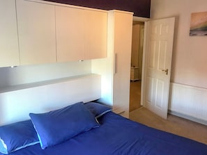 Une chambre à coucher comprenant un lit, une armoire et une porte donnant sur une autre pièce.