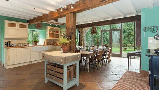 A rustic kitchen with wooden beams, a central island, and a dining area with a view of the garden. - 5 bedroom accommodation in Llansilin, near Oswestry (Llansilin, near Oswestry)