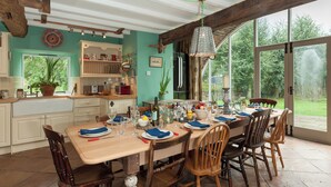 A dining area with a wooden table set for six, surrounded by wooden chairs. There is a large window providing a view of the outdoors. - 5 bedroom accommodation in Llansilin, near Oswestry (Llansilin, near Oswestry)