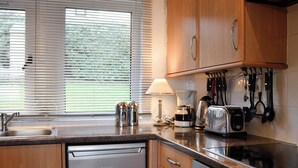 A kitchen with wooden cabinets, a dishwasher, a stove, and various kitchen appliances. - 3 bedroom accommodation in Gardenstown, near Macduff (Gardenstown, near Macduff)