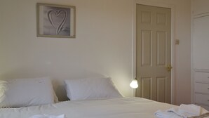A neatly made bed with folded towels, a framed artwork on the wall, and a closed door. - 3 bedroom accommodation in Gardenstown, near Macduff (Gardenstown, near Macduff)