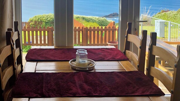 A table with a view of the ocean, wooden chairs, and a wooden fence in the background. - 3 bedroom accommodation in Gardenstown, near Macduff (Gardenstown, near Macduff)