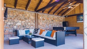 Un espace de détente extérieur accueillant, avec un mur en pierre en arrière-plan, un ensemble de canapés et une table de billard.
