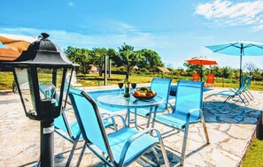 An outdoor seating area with blue chairs and a table, a lantern, and umbrellas.