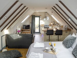 An attic bedroom with a bed, bedside table, and a kitchenette.