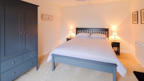 Une chambre à coucher comprenant un lit, deux tables de chevet avec des lampes, une armoire et un luminaire au plafond.