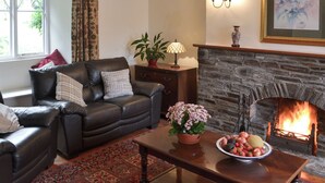 Ein gemütliches Wohnzimmer mit Kamin, Ledersofa und einem Tisch voller Früchte.