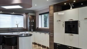 A modern kitchen with a central island, bar stools, and built-in appliances. - 2 bedroom accommodation in Clachan Sands, Isle of North Uist (Clachan Sands, Isle of North Uist)