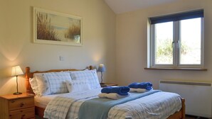 Une chambre à coucher avec un lit en bois, deux tables de chevet, une fenêtre et un tableau au mur.