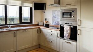 Een moderne keuken met een inbouwoven, magnetron en een groot raam met uitzicht op het landschap.