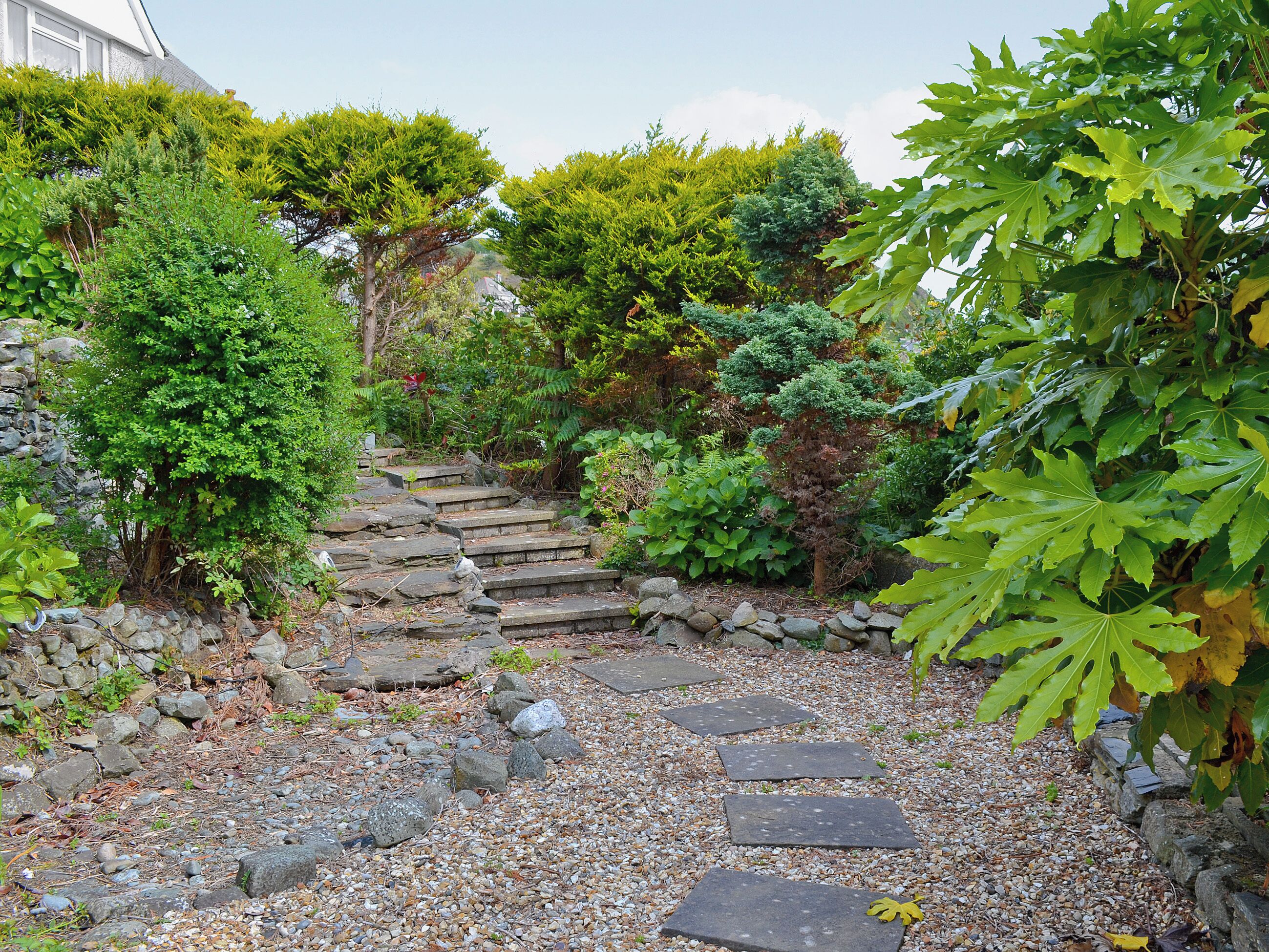 Ein Garten mit Steintreppen, die zu einem Haus führen.