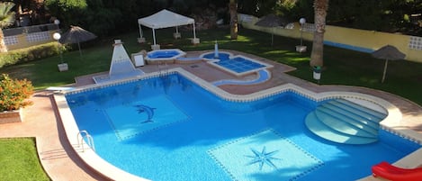 A swimming pool with a dolphin design, a slide, and a star pattern on the water.