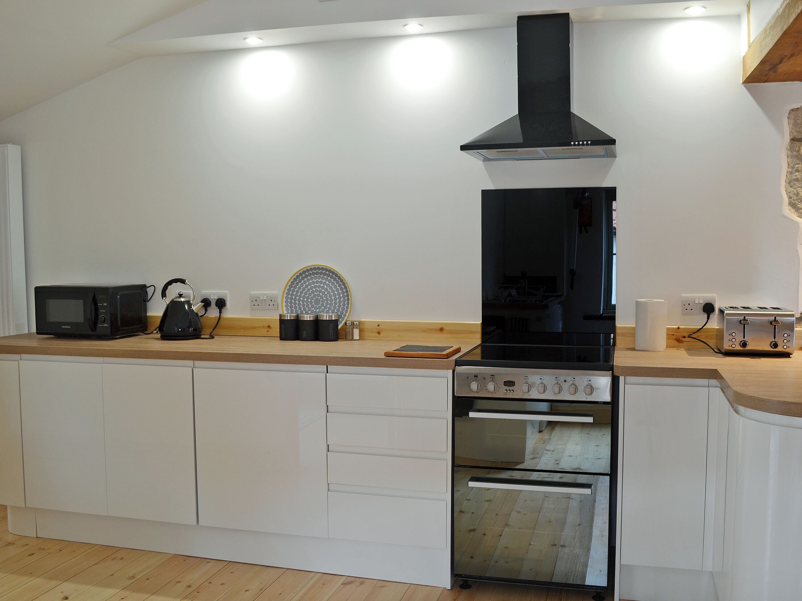 A modern kitchen with a built-in oven, microwave, and a black range hood.