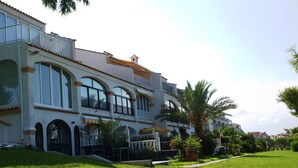 Un edificio de varios pisos con fachada blanca, ventanas arqueadas y balcones.