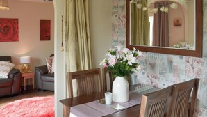 A cozy living room with a dining table, chairs, a red rug, and a floral vase. - Westville by the Stream (Rosecraddoc, near Liskeard)