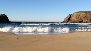 A beach with waves crashing onto the shore, a clear sky, and rocky outcrops on either side. - 2 bedroom accommodation in Aird, near Stornoway (Aird, near Stornoway)