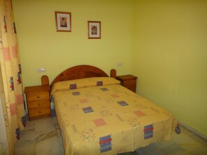 Ein Schlafzimmer mit einem Bett, zwei Nachttischen, einem hölzernen Kopfteil und einer gelben Wand.