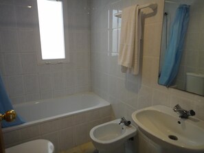 Ein Badezimmer mit einer Badewanne, zwei Waschbecken, einem Fenster und einem Spiegel.