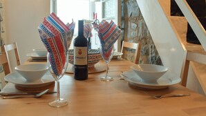 Una mesa de comedor dispuesta con copas de vino, una botella y servilletas estampadas.