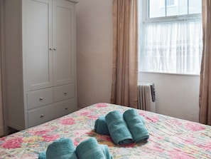 A bedroom with a bed, a wardrobe, a radiator, and a window with curtains.
