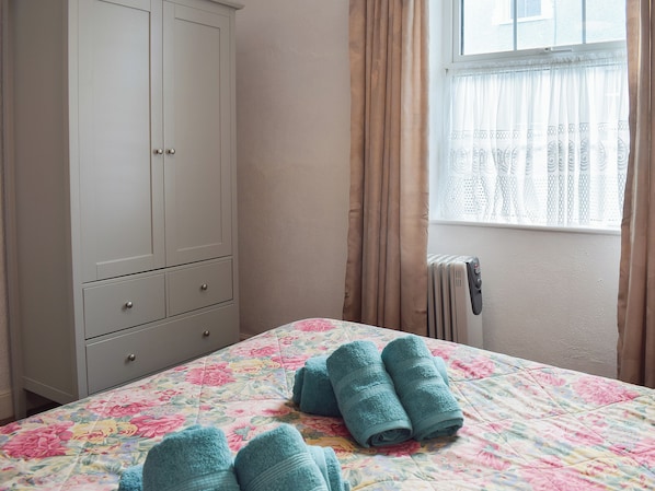A bedroom with a bed, a wardrobe, a radiator, and a window with curtains. - 3 bedroom accommodation in New Quay (New Quay)
