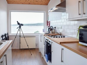 Cocina moderna con vista al mar, un trípode con cámara y servicios básicos.