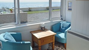 Une pièce avec vue sur la mer, une petite table, deux chaises bleues et un radiateur.