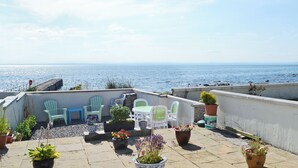 Une terrasse sur le toit offrant une vue sur la mer, des sièges en plein air et des plantes en pot.