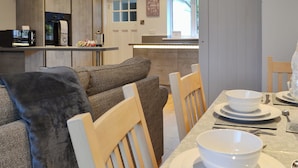 Een moderne keuken met een eethoek, houten kastjes en uitzicht naar buiten.