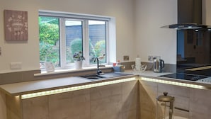 Een moderne keuken met een ingebouwd eiland, een raam met uitzicht op groen en diverse snacks op de aanrecht.