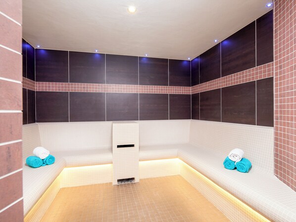 A modern spa room with a heated floor, a bench, and towels.