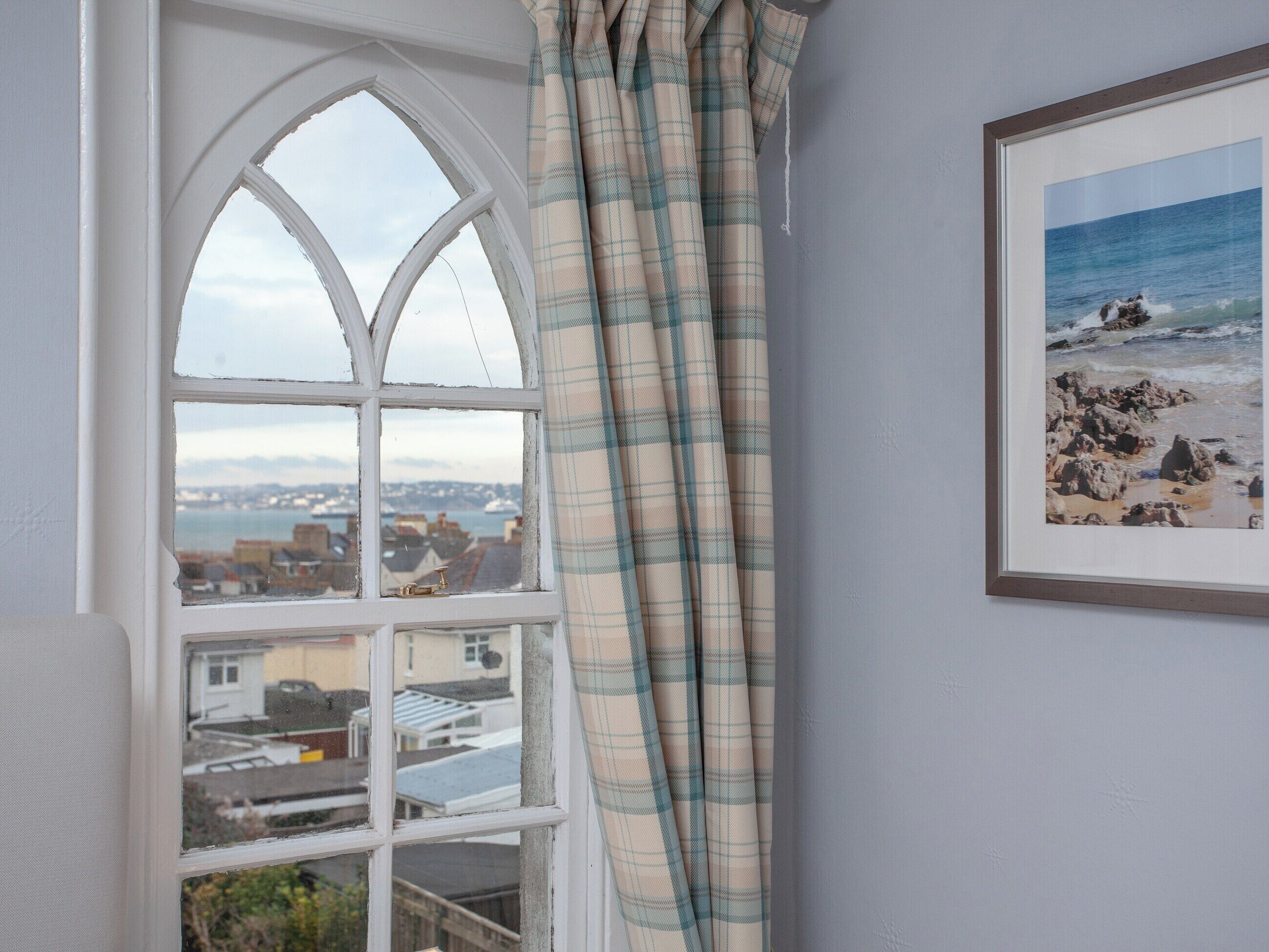 Una habitaci ón con vistas a un pueblo costero a través de una ventana con marco blanco.