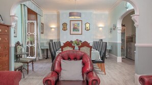 A dining area with a red leather chair, a dining table with chairs, and a chandelier. - 8 bedroom accommodation in Brixham (Brixham)