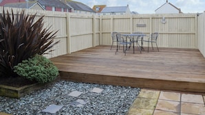 Un patio con un pavimento in legno, un tavolo e sedie, e un cartello decorativo.