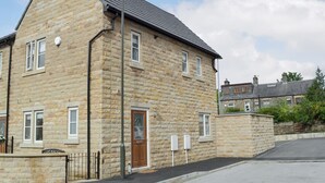 A stone building with a pitched roof, a single visible door, and a street lamp. - 2 bedroom accommodation in Glossop (Glossop)