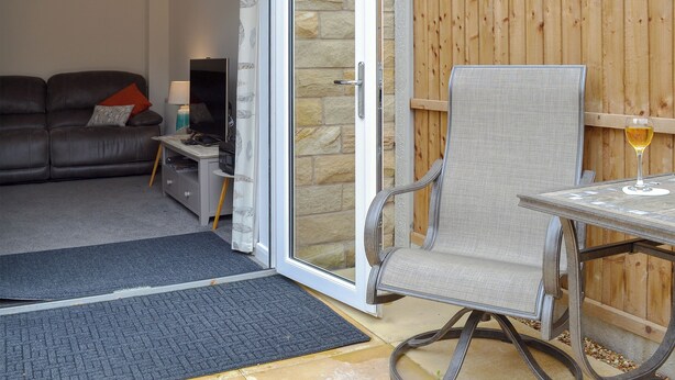 A living room with a sofa, a TV, and a table with a glass of wine. - 2 bedroom accommodation in Glossop (Glossop)