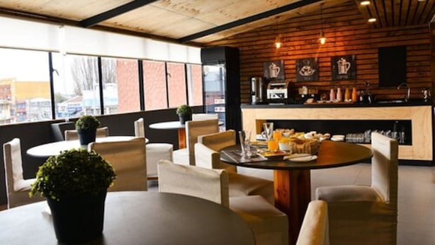 A modern cafe with wooden ceiling beams, large windows, and a bar area with coffee and tea displays. - Etnico Bío Bío (Los Angeles)