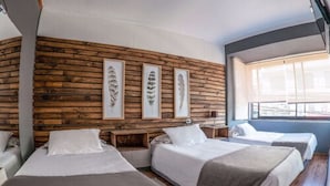 A hotel room with three beds arranged in a row, wooden paneling on the wall, and framed botanical prints. - Etnico Bío Bío (Los Angeles)