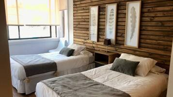 Ein Zimmer mit zwei Betten, Holzvertäfelung an den Wänden und gerahmten Kunstwerken.