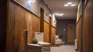 A hallway with wooden paneling, beige chairs, and a potted plant. - Etnico Bío Bío (Los Angeles)