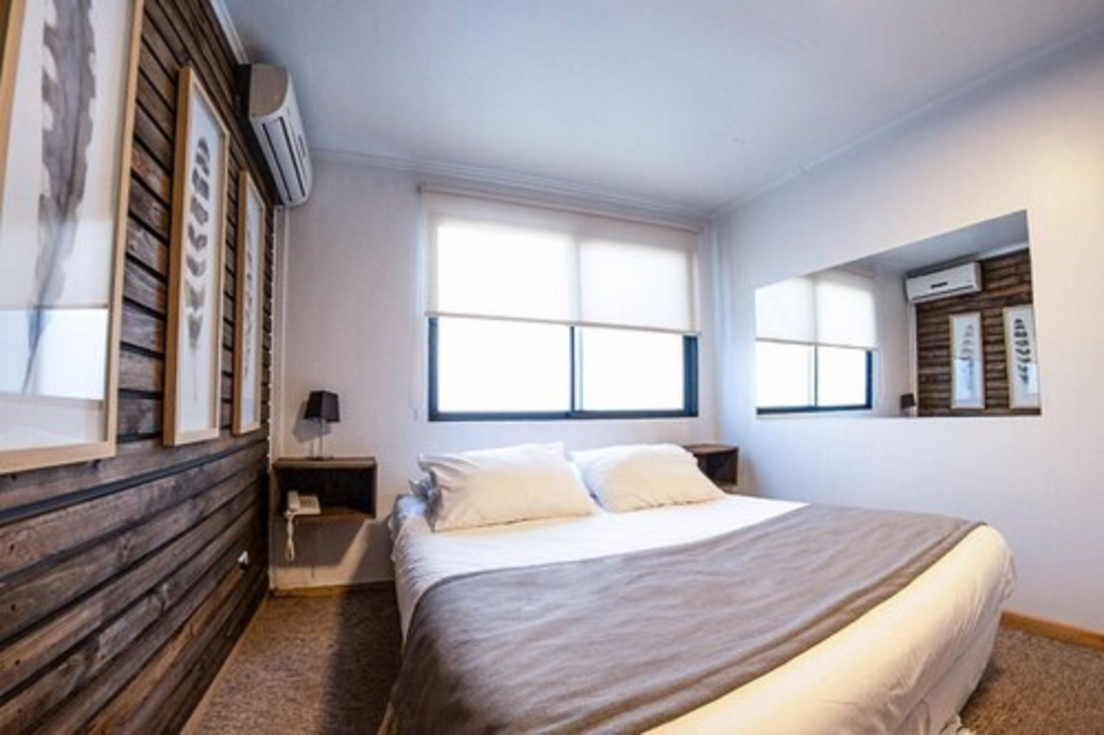 Un dormitorio con una cama, una mesita de noche, una lámpara y una ventana con persianas.
