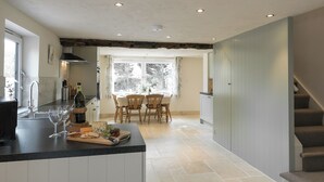 A kitchen with a dining area, a staircase, and a window with a view. - The Old Rectory Cottage (Tothill, near Louth)