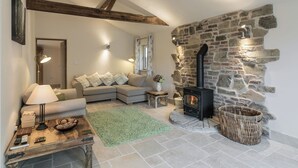 A cozy living room with a stone fireplace, a sofa, a coffee table, and a lamp. - The Old Rectory Cottage (Tothill, near Louth)