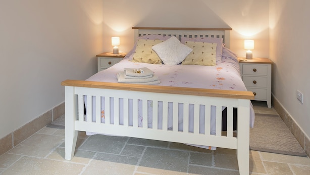 A bedroom with a bed, two bedside tables, and a nightstand. - The Old Rectory Cottage (Tothill, near Louth)